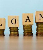 loan text written on wooden block with stacked coins